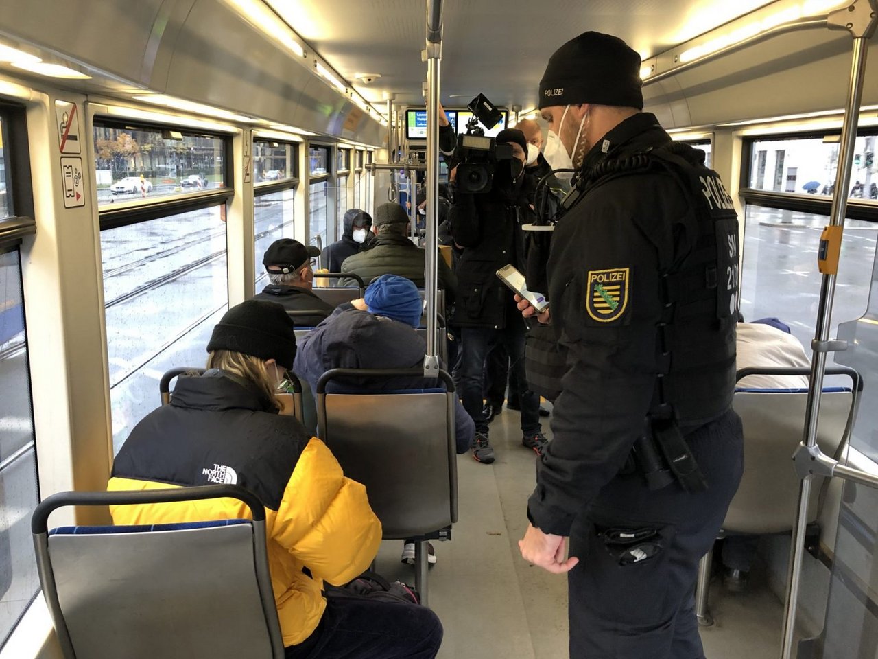 In einer Bahn kontrolliert ein Mann einen Fahrgast.