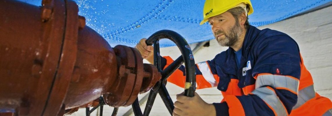 Ein Arbeiter dreht an einem großen Ventil.