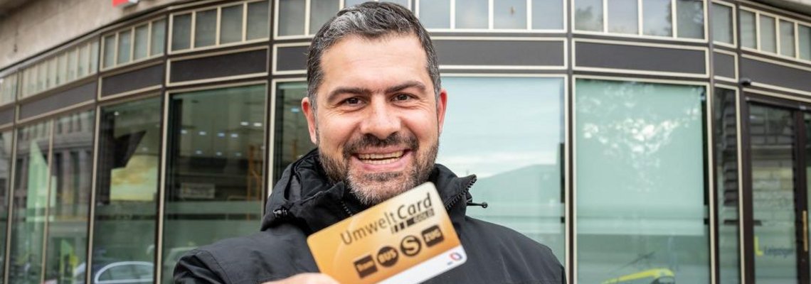 Karsten Günther hält seine Karte in die Kamera und grinst. Im Hintergrund ist ein Service Center..