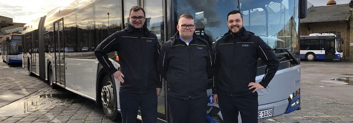 Graupeter, Uhlig und Waldenmeier stehen vor einem Bus und lächeln in die Kamera.