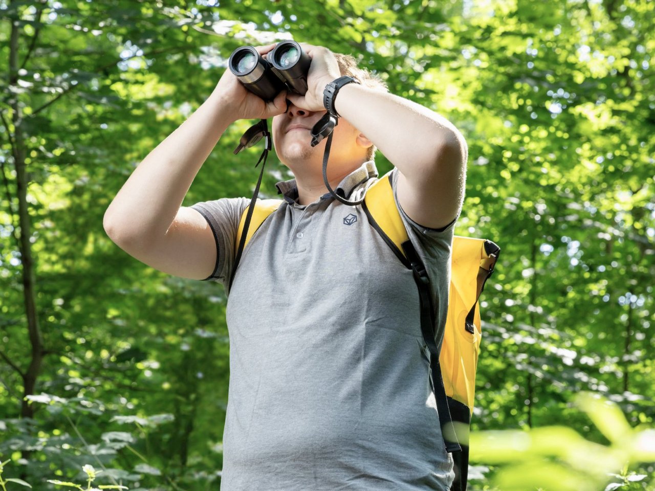 Mann mit Fernglas im Wald
