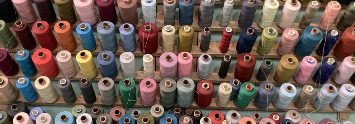 Es sind viele bunte Spulen mit Fäden zu sehen.