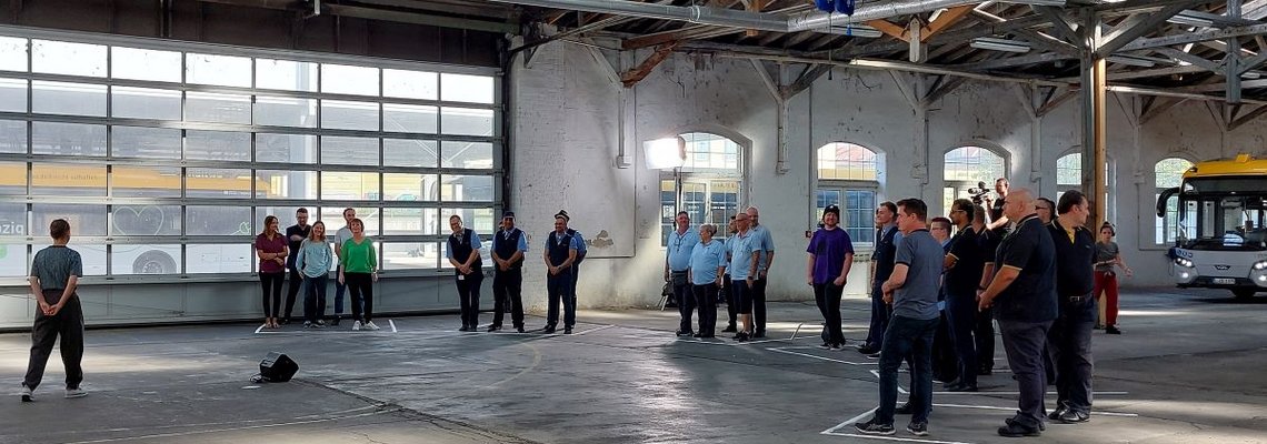 Verschiedene Gruppen von Menschen stehen in einer Lagerhalle