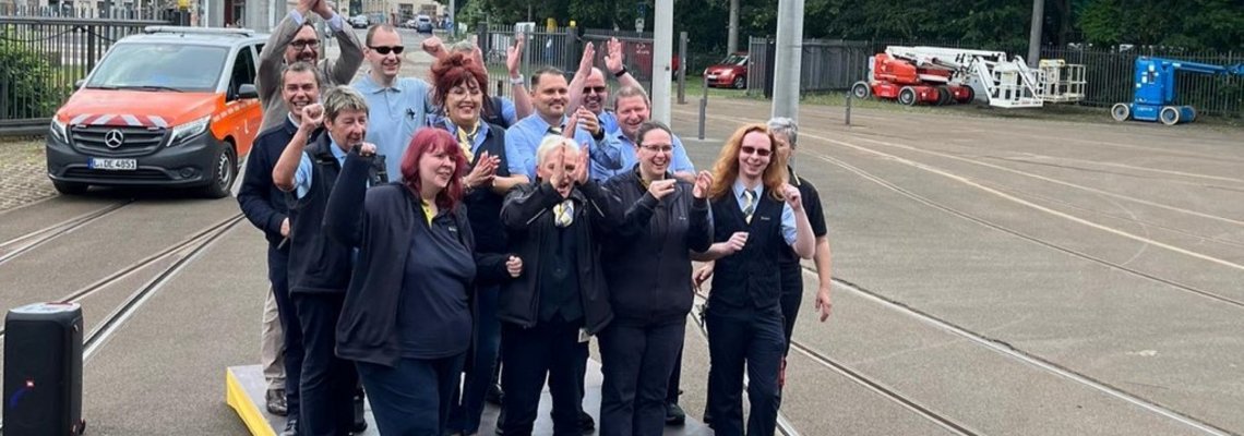 Mehrere Personen stehen auf einer Straße und grinsen in die Kamera.