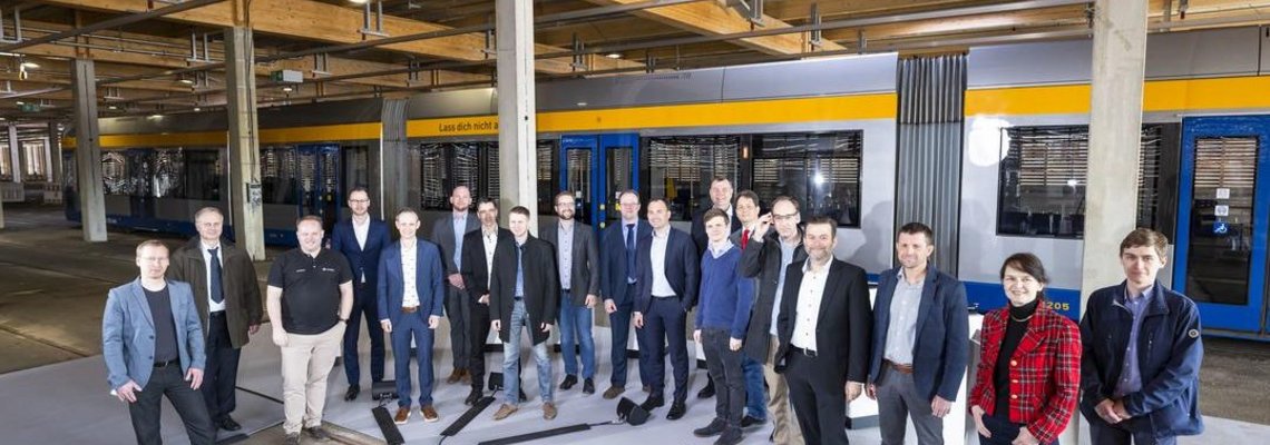 Viele Personen steht vor einer Straßenbahn in einer Halle.