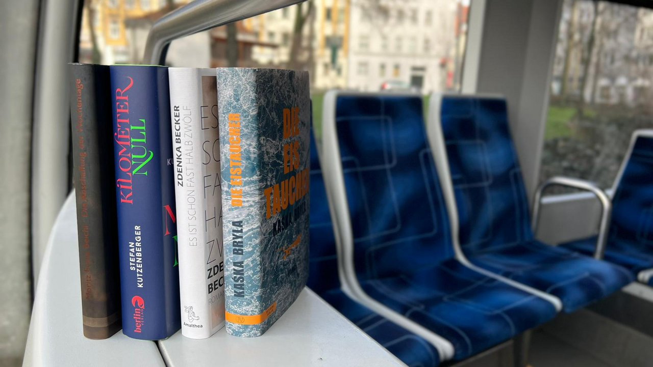 Vier Bücher österreichischer Autoren stehen aufgereiht in der Straßenbahn. 
