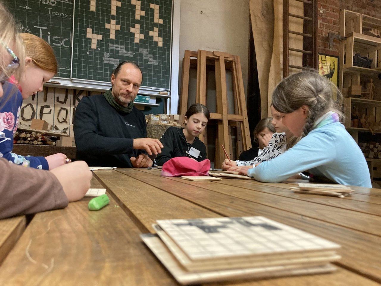 Erik Pomplitz sitzt mit mehreren Kindern an einem Tisch und unterhält sich mit ihnen.