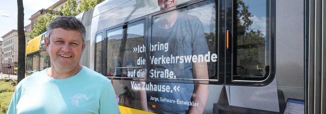 Softwareentwickler Jorge vor einer Straßenbahn mit seinem Foto