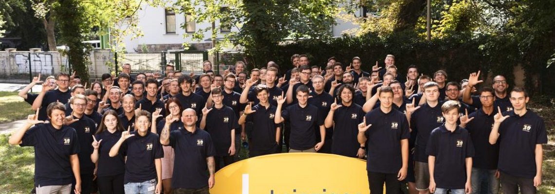 Die Auszubildenden der Leipziger Gruppe stehen um ein gelbes Banner mit der Aufschrift "Leipziger" herum.