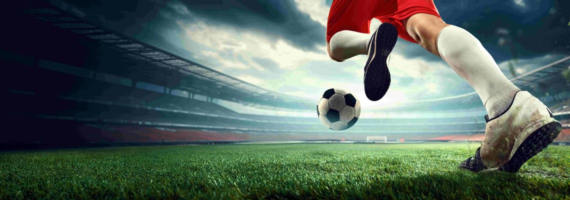 Ein Fußballer an einem Ball in einem Stadion