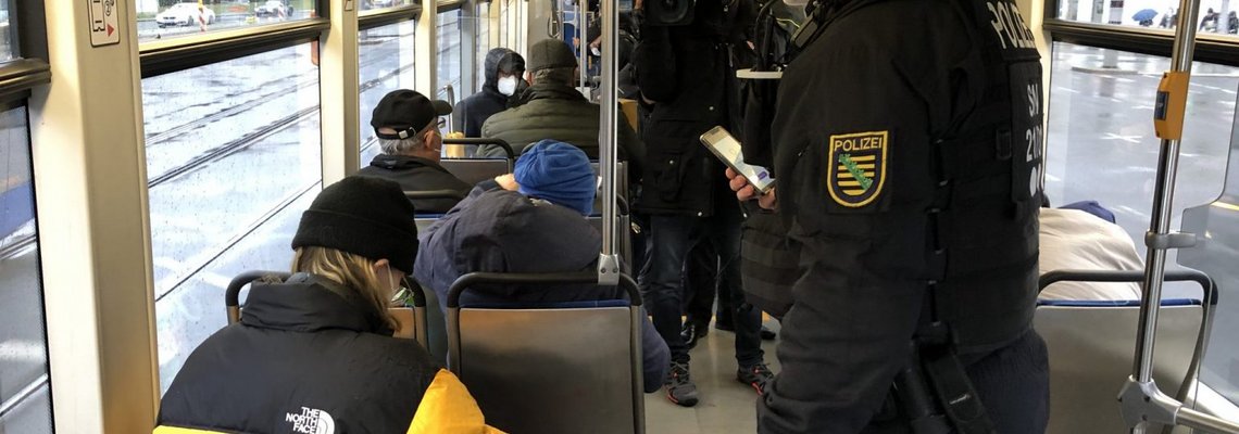 In einer Bahn kontrolliert ein Mann einen Fahrgast.