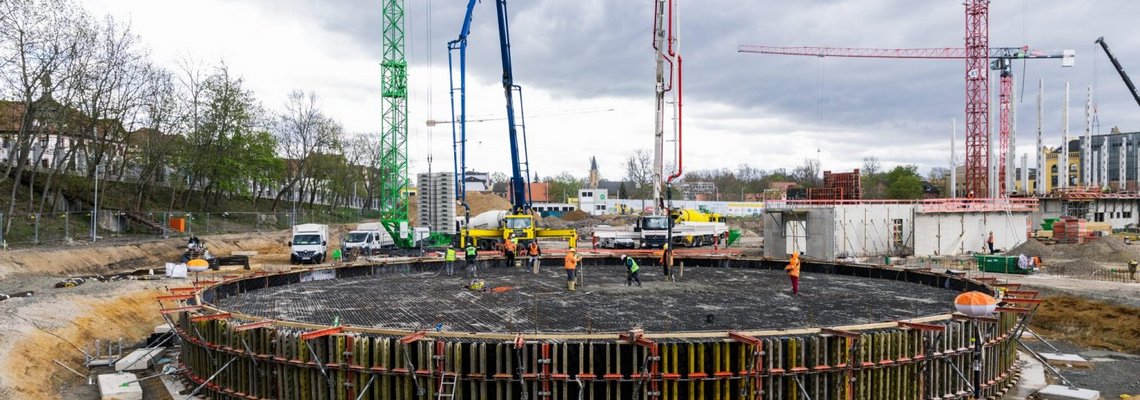 Blick auf die Bodenplatte aus Beton auf der Baustelle des HKW Süd. Mehrere Kräne stehen im Hintergrund. 