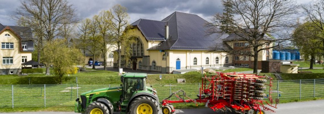 Ein Traktor mit Anhänger fährt vor dem Wassergut Canitz entlang.