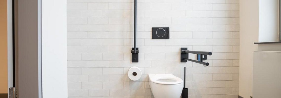 Blick in einen gefliesten Raum mit Toilette.