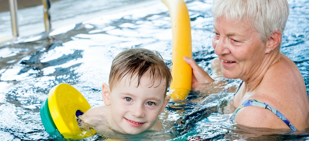 Ein Kind mit seiner Oma beim Schwimmkurs