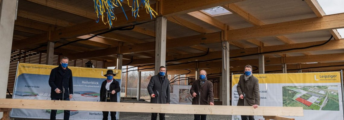 Mehrere Menschen stehen an einem Holzbalken.