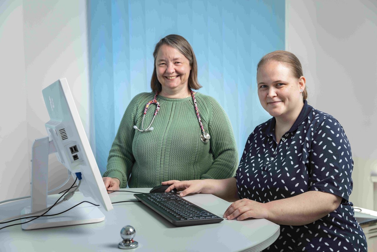 Martina Jacob und Dr. Katharina Reuse stehen an einem Tisch mit PC.