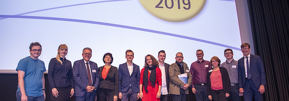 Zeugnis Übergabe im Oktober 2019: Einige Personen stehen auf einer Bühne.