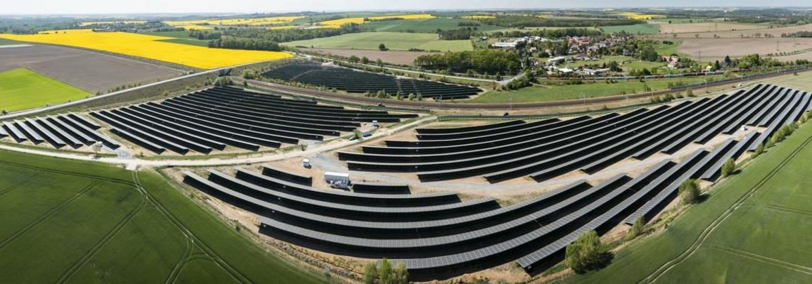 Ein großer Solarpark umgeben von Feldern aus der Vogelperspektive