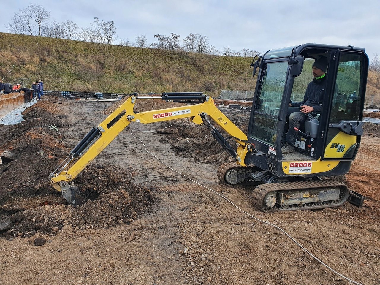 Ein kleiner Bagger steht vor einem Haufen Sand.