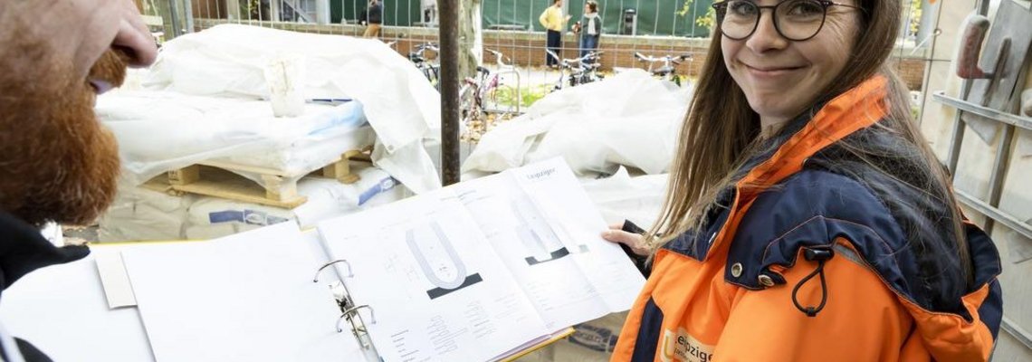 Franziska Loebelt steht mit einem geöffnetem Ordner in der Hand auf einer Baustelle.