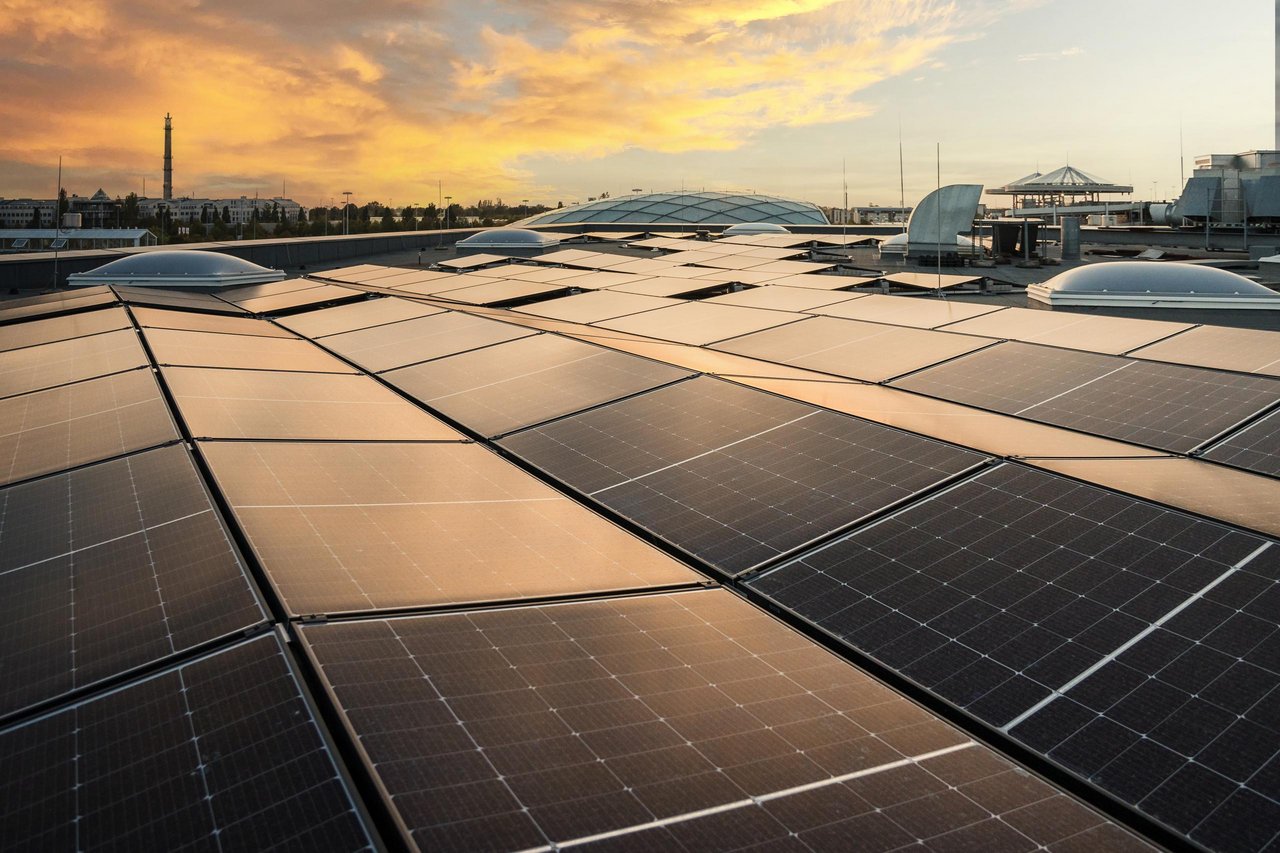 Über einer PV-Anlage geht die Sonne unter und taucht alles in ein orangenes Licht.