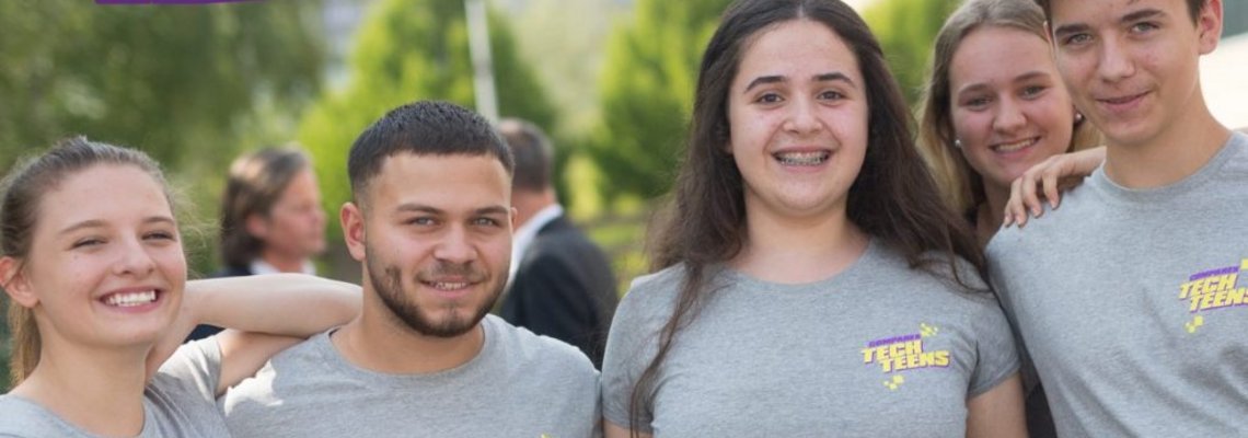 Vier TechTeens stehen der Kamera zugewandt und lächeln. Sie alle tragen graue TechTeens-Shirts.